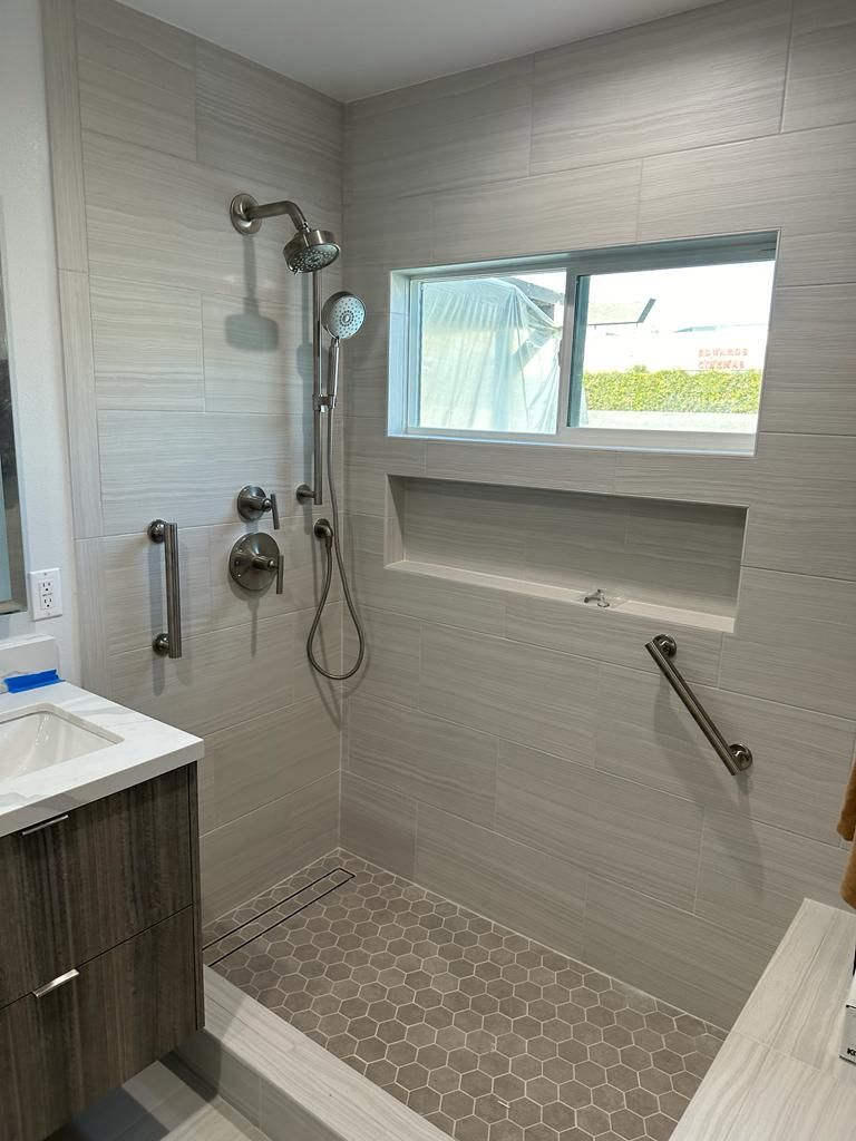 Tiled walk-in shower with a linear floor drain and a recessed wall niche